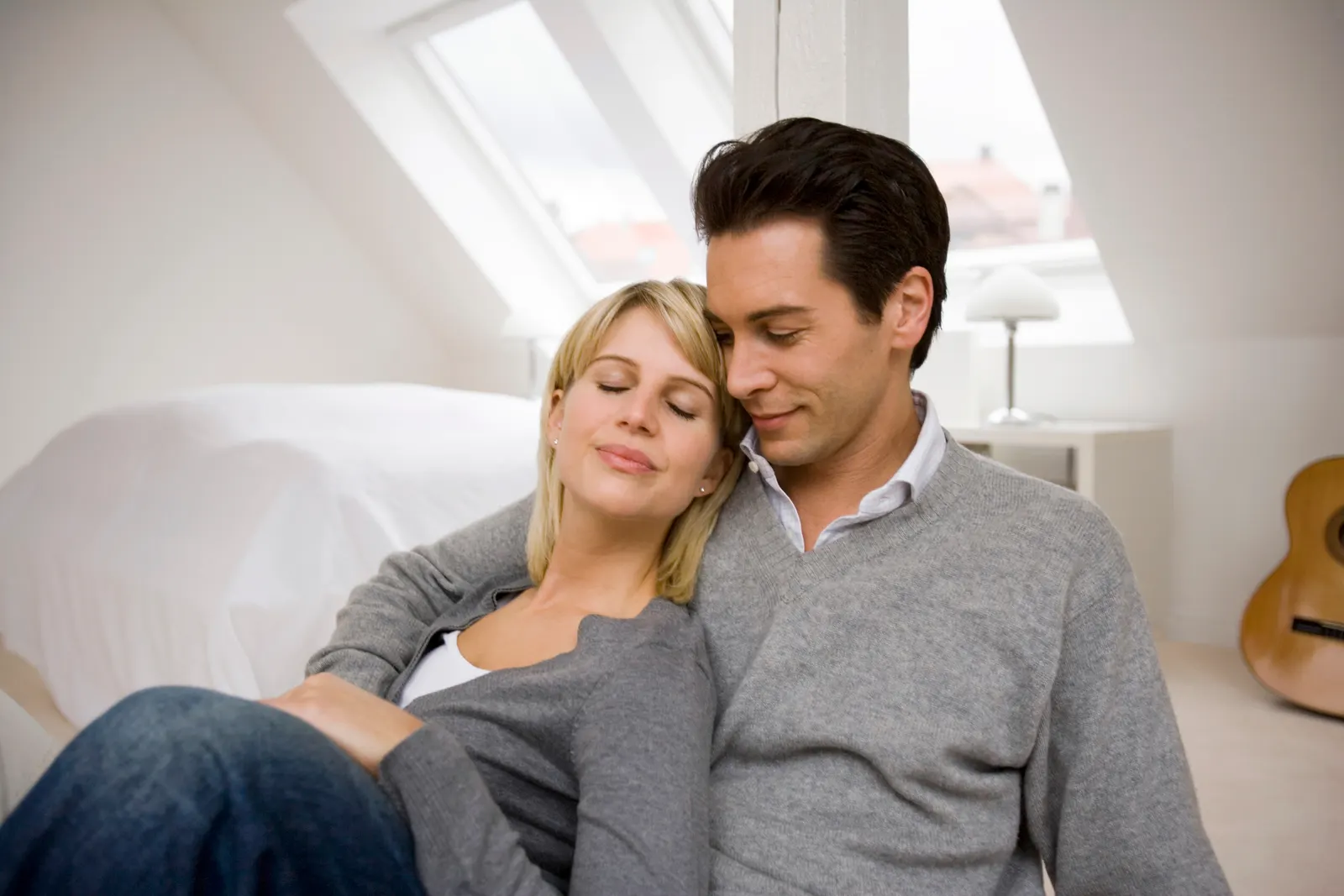 Woman resting her head on her partner's shoulder at home