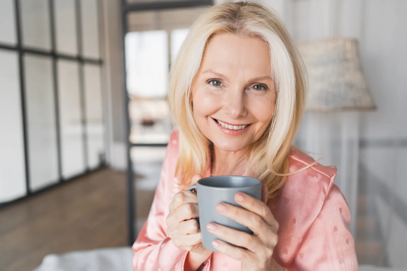 Smiling woman holding a cup of coffee at home in the morning